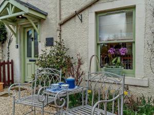 two chairs and a table in front of a house at 1 Bed in Hawick oc-91437 in Denholm