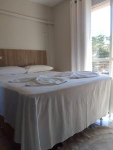 a white bed in a room with a window at Suíte até 3 pessoas, Centro, Piscina in Foz do Iguaçu