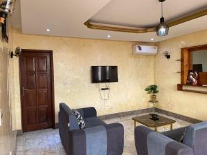 a living room with couches and a tv on the wall at DAVAROXE Appartements Lingwala RTNC in Kinshasa