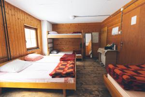 two beds in a room with wooden walls at Tamar Mountain hut in Rateče