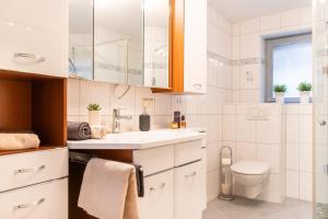a white bathroom with a toilet and a sink at Lago Edera - Talblick in Hemfurth-Edersee +30 photos