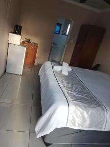 a bedroom with a bed with white sheets and a refrigerator at DAX BnB in Cedarville