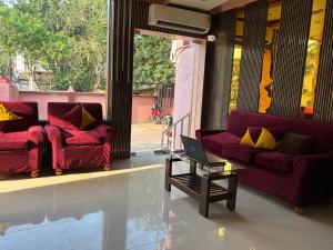 a living room with two red couches and a laptop on a table at Hotel Kep's - A Business Class Hotel in Contai