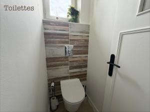a bathroom with a toilet and a wooden wall at Appartement paisible in Limoges +6 photos
