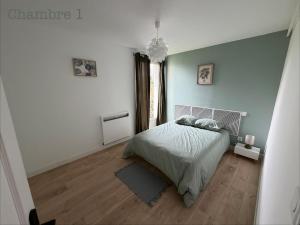 a white bedroom with a bed and a wooden floor at Appartement paisible in Limoges
