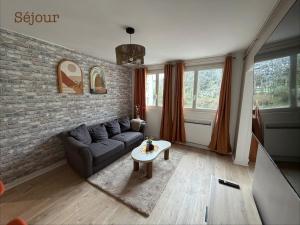 a living room with a couch and a brick wall at Appartement paisible in Limoges