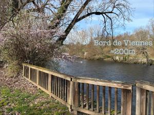 a wooden fence next to a river with trees at Appartement paisible in Limoges
