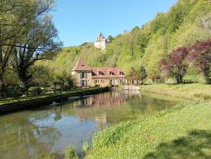 a house on the side of a river with a building at Gîte du Domaine du Moulin de la Roque in Castels