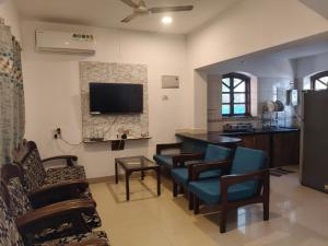 a living room with chairs and a flat screen tv at The Coastal Villa Arpora in Parra