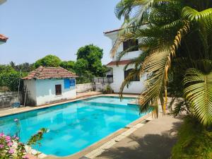 a swimming pool in front of a house with a palm tree at The Coastal Villa Arpora in Parra