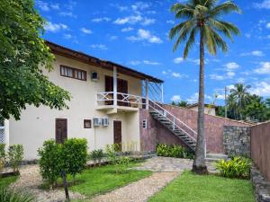 a house with a staircase and a palm tree at Pousada Montemar in Ilhabela