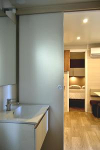 a bathroom with a sink and a room with a bed at Camping 4 Cerchi Ecogreen in Lido di Fermo
