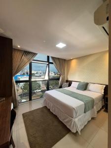 a bedroom with a large bed and a large window at Hotel Universal in Santarém