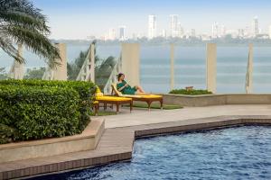 a woman sitting in a chair next to a swimming pool at The Oberoi Mumbai in Mumbai