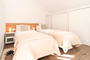 two beds in a bedroom with white walls and wood floors at Attic Duplex Apartment with 4 terraces & 5 min walk to Beach in Denia +22 photos