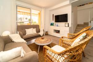 a living room with a couch and chairs and a tv at Attic Duplex Apartment with 4 terraces & 5 min walk to Beach in Denia