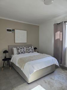 a white bedroom with a large bed and a window at The041Stay in Gqeberha