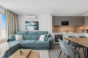 ein Wohnzimmer mit einer blauen Couch und eine Küche in der Unterkunft SUNLIGHT Spain in Manilva