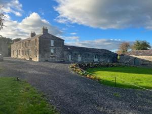 an old stone building on a road with a green yard at Crossdrum Courtyard Accommodation in Oldcastle