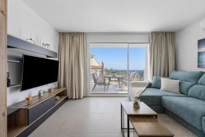 ein Wohnzimmer mit einer blauen Couch und einem Fernseher in der Unterkunft SUNLIGHT Spain in Manilva
