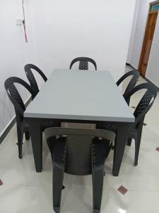 a white table with black chairs around it at Ocean waves in Trincomalee +3 photos