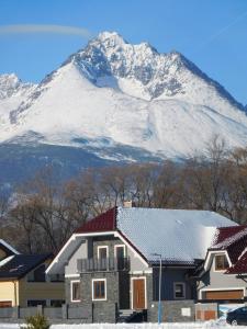 a house with a snow covered mountain in the background at TaTanKa apartments in Batizovce