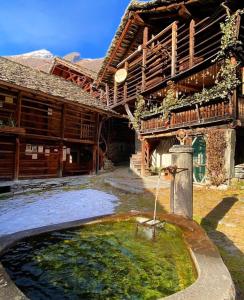 a house with a water fountain in front of it at Baita Genepy - Charme Alpino in Pietra in Alagna Valsesia