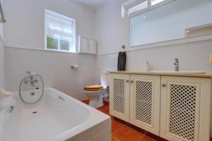 a bathroom with a tub and a toilet and a sink at Sunbird Cottage - Wilderness in Wilderness +18 photos