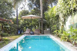 a swimming pool with two chairs and an umbrella at Colonial Residence Kandy Boutique Bungalow in Kandy
