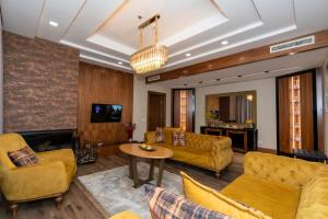 a living room with yellow couches and a table at Hotel Golden Palace in Shkodër