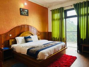 a bedroom with a bed with green curtains and a window at Hotel Sumit in Kausani