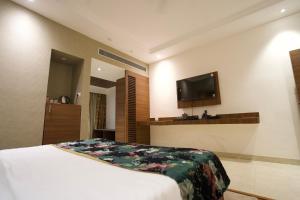 a hotel room with a bed and a flat screen tv at RANIKOTHI BOUTiQUE HOTEL in Nagpur +4 photos