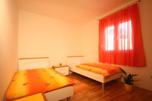 a bedroom with two beds and a window with red curtains at Apartments Beverly in Omiš
