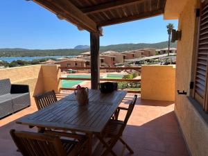 a wooden table on a patio with a view of a pool at Casa Vacanza con Piscina e Accesso diretto al Mare in Santa Marinella