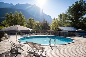 a swimming pool with two chairs and an umbrella at Huttopia Vallouise in Vallouise +19 photos
