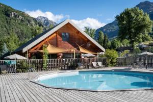 a house with a swimming pool in front of a cabin at Huttopia Vallouise in Vallouise