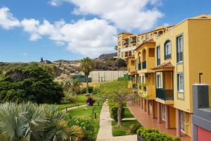 a row of buildings with palm trees and bushes at Hotel-Apartamento Las Olas in Los Cancajos