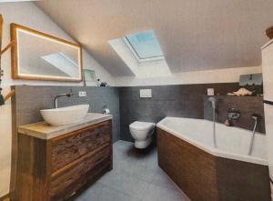 a bathroom with a sink and a tub and a toilet at Das Alpenhostel in Brannenburg