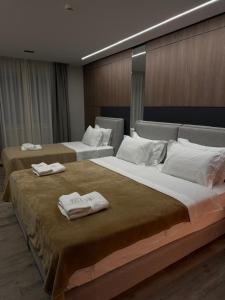two beds in a hotel room with towels on them at Hotel Liss in Lezhë