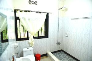 a bathroom with a shower and a toilet and a window at Hostel Kiliwood in Moshi