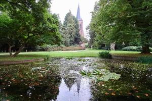 a pond with flowers in a park with a church at Spoor 24 in Dieren