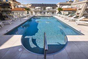 a large swimming pool with chairs and a building at Almara Green Hotel in Rimini