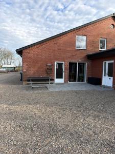 a brick building with a bench in front of it at Højmosegård ÅBENT HEMS in Varde