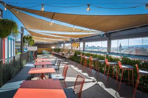a rooftop patio with tables and chairs and views of the city at Occidental Barcelona 1929 in Barcelona