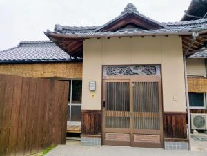 a house with a gate and a fence at ゲストハウス青い輝き in Marugame