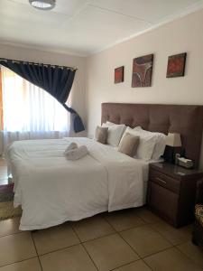 a bedroom with a large white bed and a window at Lens BnB Guesthouse in Benoni +13 photos