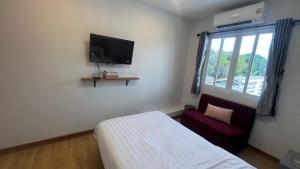 a bedroom with a bed and a tv on the wall at บ้านตลาด สัตหีบ in Sattahip