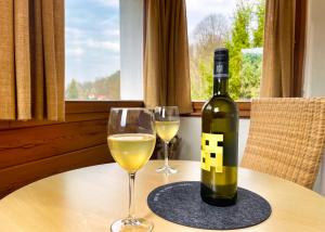 a bottle of wine and two glasses on a table at Pension Zum Talwächter im Sandsteinidyll in Rathen