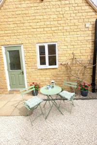 a table and two chairs in front of a brick building at Modern Cotswolds Studio in Bishops Cleeve +2 photos