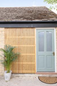 a wooden shed with a door and a potted plant at Modern Cotswolds Studio in Bishops Cleeve